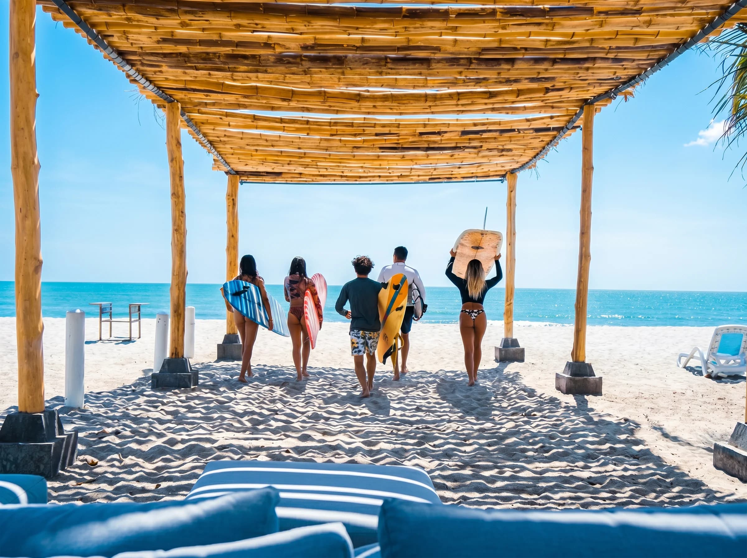Un grupo de amigos camina con sus tablas de surf hacia el mar en Playa Caracol