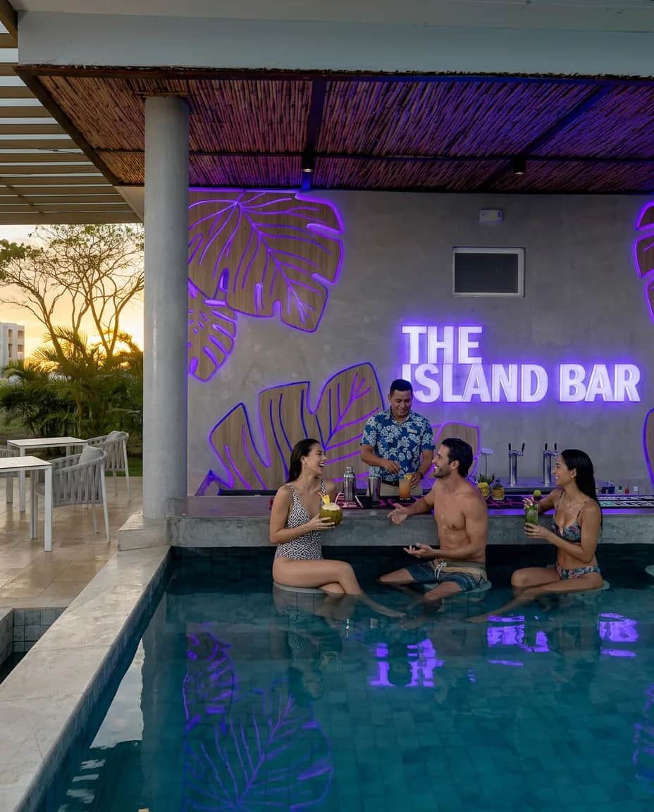 The Island Bar lit up at dusk, with guests in the pool